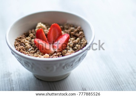 Yummy muesli breakfast with fresh strawberry in the white plate on the gray wooden background.