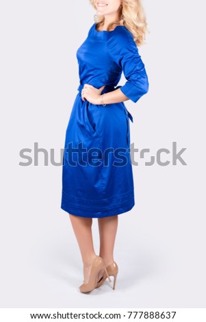Unrecognizable model wearing dress posing on grey neutral background.