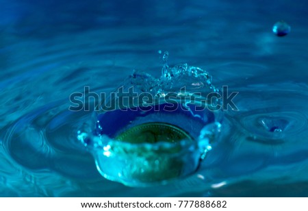 Coin Dropping  in water, blue closeup, macro. drop visible coin money 