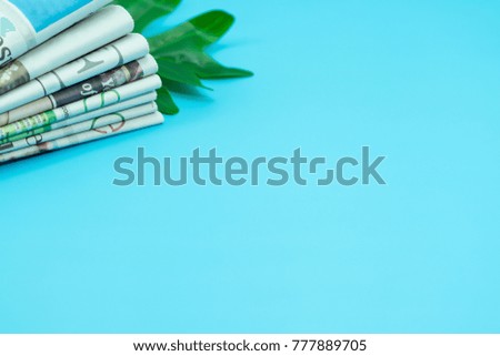 Stack newspapers with leaves on blue background.  