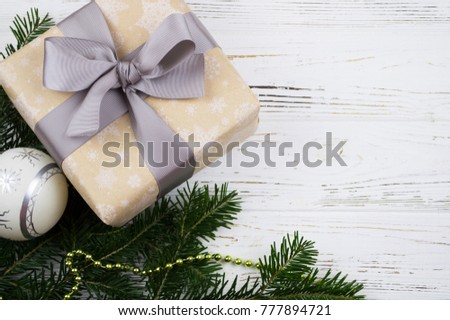 a gift box with a bow, a Christmas tree branch, a Christmas toy on a wooden white background. new year background