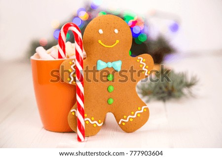 Gingerbread man standing next to orange mug and new year light bokeh background. Copy space for text.