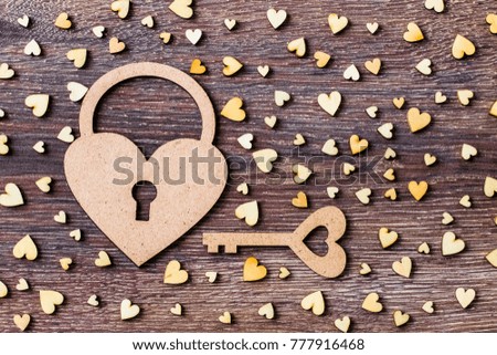 Lock and key on a background of wooden hearts. Background with a lock, a key and a lot of wooden hearts.