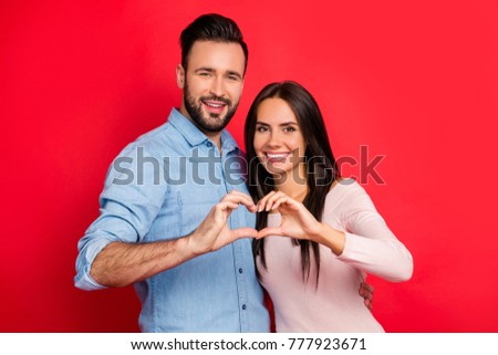 Concept photo of love story of cheerful, attractive, lovely, cute, sweet couple in casual outfit making heart with fingers over red background, ideal wife and husband on 14 february