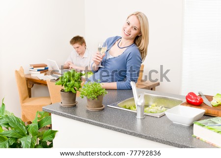 Happy woman cook enjoy white wine in kitchen, man in background