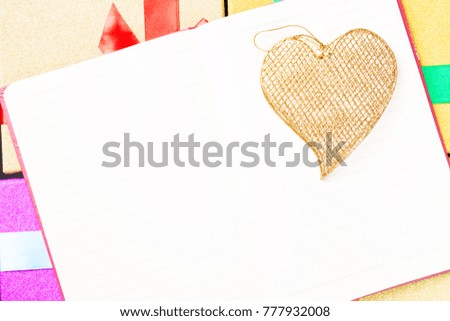 Valentine day concept. Blank note book with gold decorative heart on gift box background. Free space for your text.