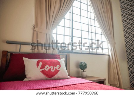 Single bed with pillow with love sign,  looking comfortable next to the big window.