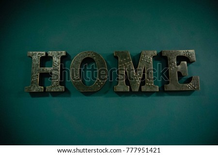 Home sign letters in interior, green background. Image contain certain grain or noise and soft focus