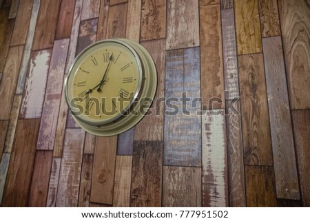 Vintage wall clock hanged on the wall showing five minutes past eight oclock. Wooden background. Image contain certain grain or noise and soft focus