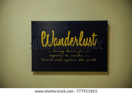 Hanged sign with motivational wordings - wanderlust . Plain background. Image contain certain grain or noise and soft focus