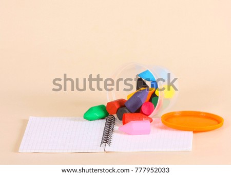 A lot of crayons fell out of the can on the notebook in a cage. Stationery for drawing. Horizontal studio image.