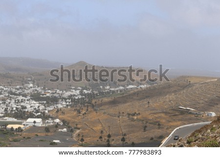 A view of cloudy weather on the old volcano crater and at the foot of the town is located Aria with white houses, the island of Lanzarote, Spain.