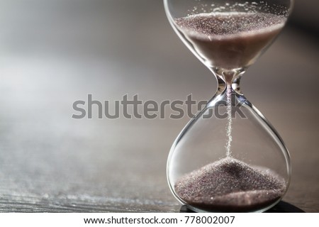 Modern hourglass on wooden background with copy space. Hourglass time passing concept for business deadline, urgency and running out of time. Royalty-Free Stock Photo #778002007