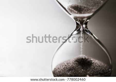 Modern hourglass with bright background for copy space. Hourglass time passing concept for business deadline, urgency and running out of time. Royalty-Free Stock Photo #778002460