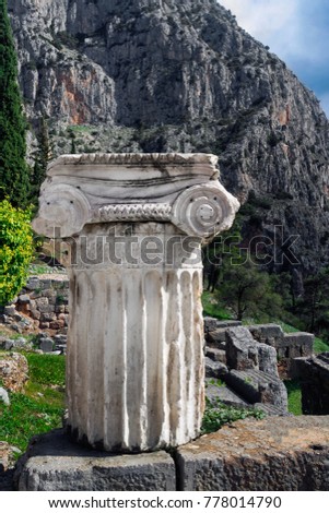 Ancient column in Ancient Greek archaeological site of Delphi shown at warm evening light, Central Greece