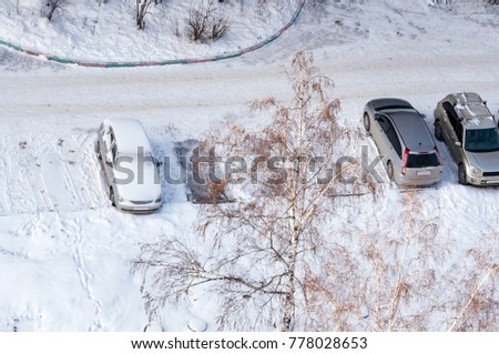 Several cars in street parking covered with snow after a snowfall. View from above