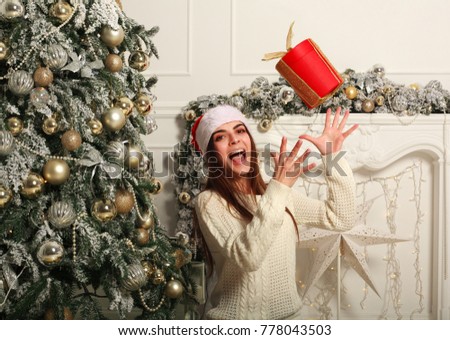 Joyful young woman with gift in Santa hat on the background of Christmas decorations