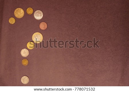 On a gray background, a question mark made up of small coins. Family budget, money issue, lack of funds. View from above.