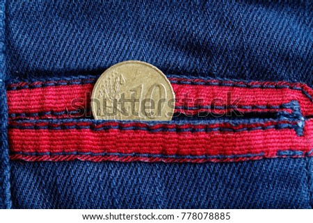 Euro coin with a denomination of 10 euro cent in the pocket of worn blue denim jeans with red laces
