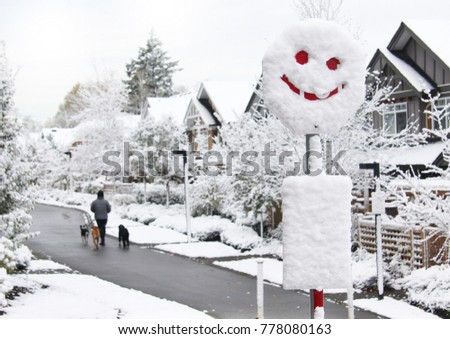 Happy friendly Neighbourhood in winter. Happy face written in snow on the stop sign. 