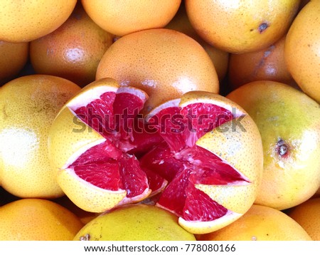 Colorful grapefruit background with many whole fruit and one sliced open with red flesh inside and space for text.