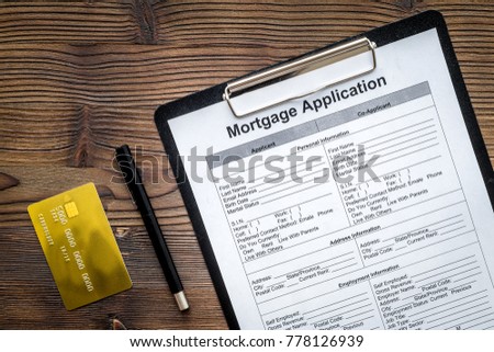 Mortgage application near bank card on dark wooden background top view