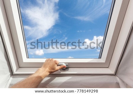 Man close new skylight (mansard window) in an attic room against blue sky Royalty-Free Stock Photo #778149298