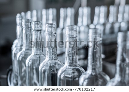 Empty glass bottles on the conveyor. Factory for bottling alcoholic beverages. Production and bottling of alcoholic beverages. Royalty-Free Stock Photo #778182217