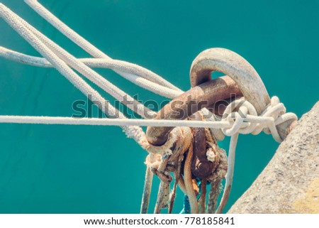 Rusty mooring ring with tied rope