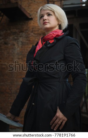 Noir film style woman in a black suit and red dress posing in a street
