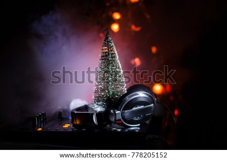 Dj mixer with headphones on dark nightclub background with Christmas tree New Year Eve. Close up view of New Year elements or symbols (Santa Clause, Snowman, Dog 2018, gift box) on a Dj table.