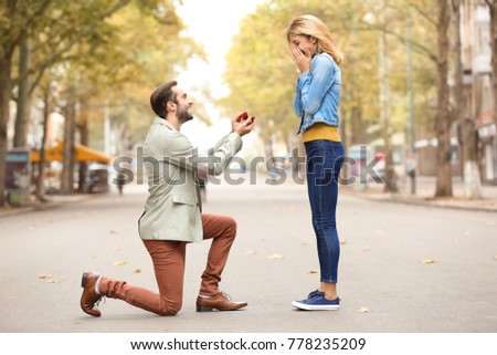 Young man with engagement ring making proposal to his beloved girlfriend outdoors Royalty-Free Stock Photo #778235209
