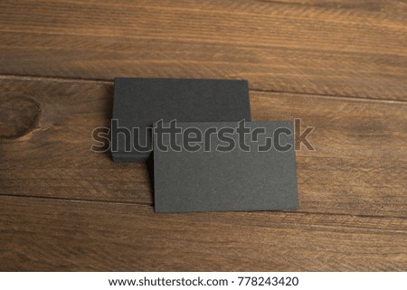 Black business cards on wooden background. Mockup.