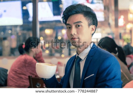 A young asian man who drinks coffee in a cafe
