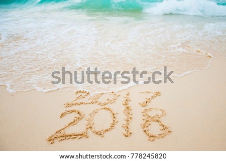 2017 is going end of year and Happy new year 2018 written on sand beach with blue wave, New Year 2018 is coming concept. Royalty-Free Stock Photo #778245820