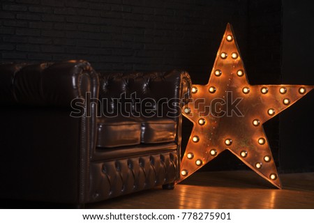 Interior of living room in dark tones with a large leather sofa and lamp star.