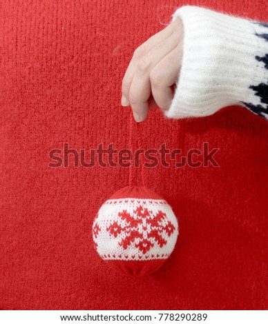 Person in winter sweater holding Christmas balls in hand. Close up, copy space, vertical composition.