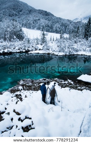 men taking photos on beautiful emerald green lake zelenci in winter scenery, Kranjska Gora, Slovenia