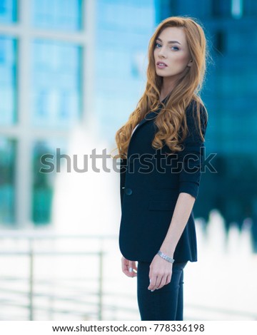 Happy woman standing outdoors in business casual suite against modern mall
