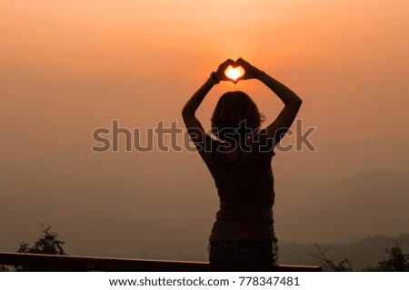 Heart shape at sunset from girl