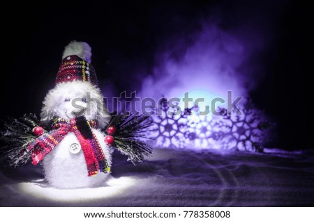 New Year. The snowman unloads gifts for the new year. White snowman surrounded by Christmas trees on evening background. Toy Decoration. Selective focus