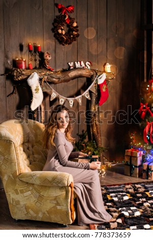 New Year and Christmas 2018. Beautiful girl holding a gift in the hands near the Christmas tree and a fireplace