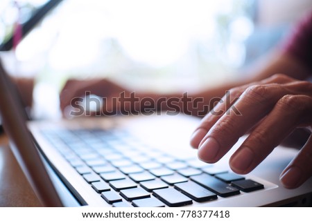 Man working by using a laptop computer on wooden table. Hands typing on a keyboard. Royalty-Free Stock Photo #778377418