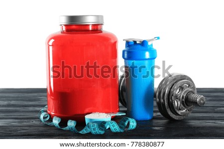 Protein shake in bottle, powder and dumbbell on table