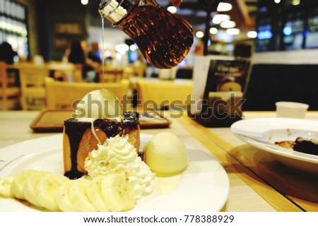 Chocolate toast with banana,vanilla ice cream,whip cream on white plate and pouring honey syrup. Delicious dessert with copy space for your text design.Concept for dessert or coffee shop.Blur picture.