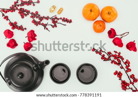 top view of chinese new year composition with tea and branches of berries isolated on white