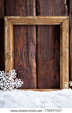 Christmas background - picture frame and snowflakes on snow and wooden wall