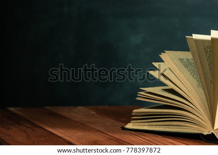 One open old book on a red wooden table. Beautiful dark background.