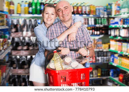 Cheerful woman and man with shopping basket in the supermarket