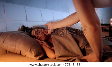 A little girl is sleeping while her mother comes in to cover her with the bed sheets, and then touches her face before leaving. Mother feels temperature of sleeping little girl checking for fever Royalty-Free Stock Photo #778454584